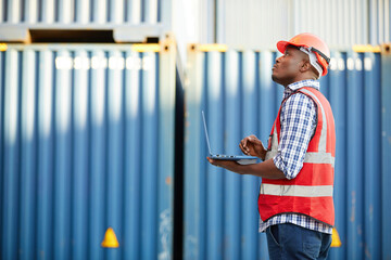 African factory worker or engineer using laptop computer and checking work in containers warehouse...