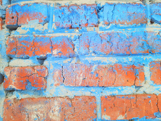 A brick wall of orange brick with traces of blue paint.