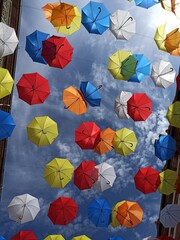 Paragüas en el cielo. Decoracion de una calle en la ciudad. Paragüas de colores colgados decoran las calles de una ciudad. Paragüas forman un patron de colores.