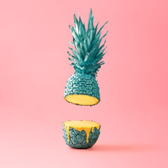 Bright, creative concept of fruit and summer on a pink background. Blue sliced pineapple bleeds yellow paint.