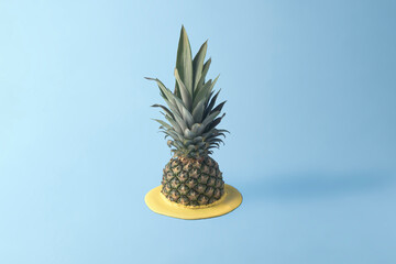 Pineapple melts in yellow paint on a blue background with copy space. Creative fruit concept.