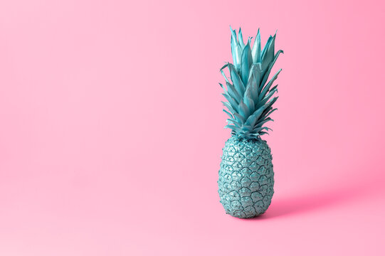 Bright creative food concept. Blue pineapple on a pink background with copy space.