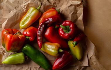 Pile of different peppers on craft paper. Organic ugly vegetables. Top view with copy space