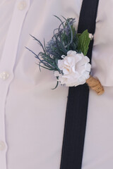 Groom in white shirt with boutonniere. Flower design, floristry. Wedding day and accessories, copy...