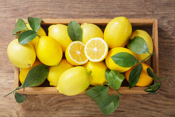 wooden box of fresh lemons with leaves, top view