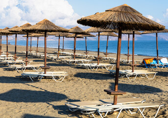 Empty beach with sun loungers and umbrellas in the early morning on a sunny day on the Crete island Greece. . High quality photo