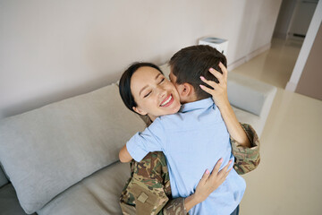 Woman in camouflage clothes and teenage boy hugging each other