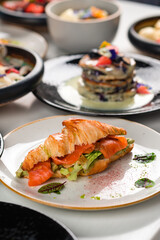 Croissant sandwich with cream cheese, salmon and arugula on a white plate, Healthy breakfast concept.