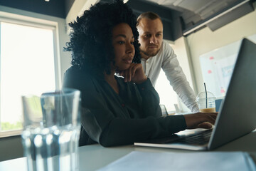 Manager helping female colleague with project work