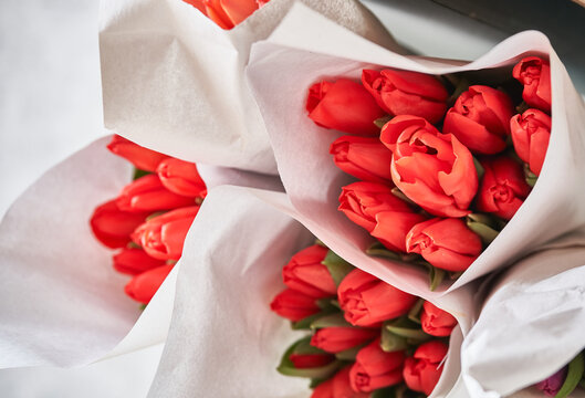 Lots of delicate bouquets of red tulips, top view. A selective focus of beautiful red tulips in a package.The concept of preparation for congratulations. High quality photo