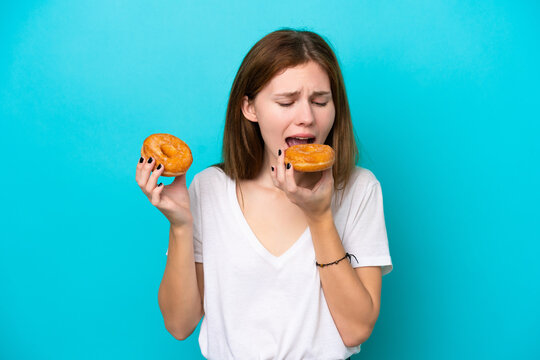 Young English woman isolated on blue background eating a donut