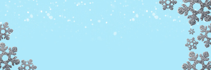 Silver snowflakes side framing light blue web banner with snow bokeh