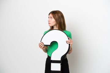 Young English woman isolated on white background holding a question mark icon and looking side
