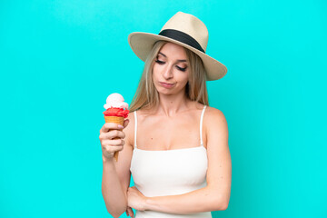 Blonde woman in swimsuit holding an ice cream isolated on blue background with sad expression