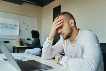 Tired man with closed eyes sitting at his desk