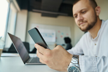 Young man with phone in his hands works in office