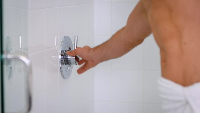 Close-up of a man's hand turning on the shower before entering.