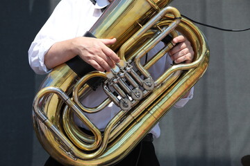 Obraz na płótnie Canvas A person in a white shirt playing a musical instrument tuba close-up