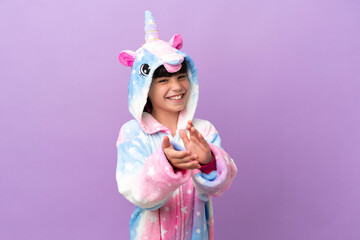 Little kid wearing a unicorn pajama isolated on purple background applauding after presentation in a conference