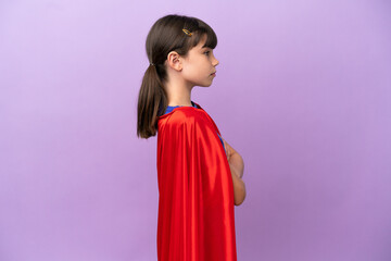 Little kid isolated on purple background in superhero costume with arms crossed