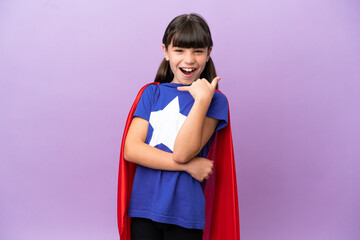 Little kid isolated on purple background in superhero costume and doing phone gesture