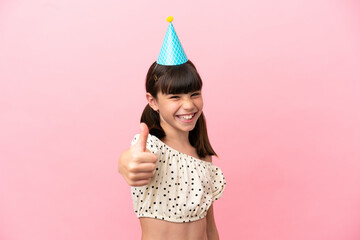 Little caucasian kid with birthday hat isolated on pink background with thumbs up because something good has happened
