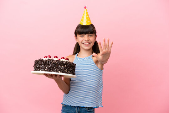 Little caucasian kid holding birthday cake isolated in pink background counting five with fingers