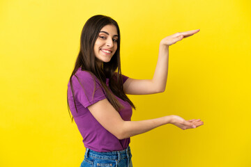 Young caucasian woman isolated on yellow background holding copyspace to insert an ad