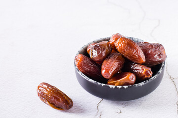 Ripe dried dates in a bowl on the table. Oriental dessert