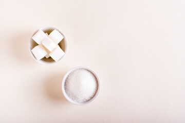 Sugar cubes and granulated sugar in bowls. Choosing between types of sugar. Top view