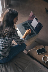 A young woman working on a laptop at home.