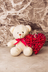 White Teddy bear with red heart on grey wall background
