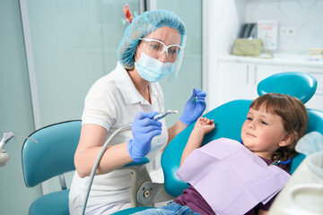 Scared female child is staring at pedodontist before teeth-polishing procedure