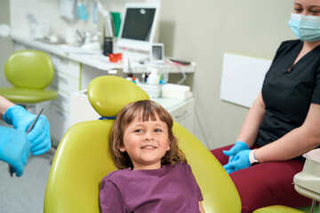 Joyful female child posing for camera in stomatologist office