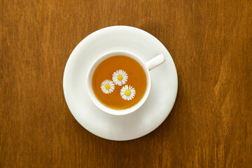 Cup of chamomile tea on wooden background, flat lay.