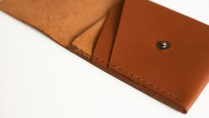 Opened empty orange genuine leather card holder on a white surface.