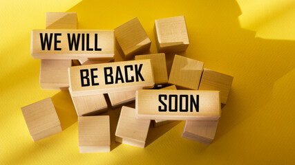 We will be back soon, text on wooden blocks and yellow background