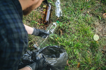 Obraz premium Close-up, a plastic bottle in a male hand, cleaning up nature.