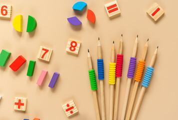 Wooden toy blocks. School supplies, math fractions, pencils, numbers, on beige background. Back to school, education concept background	