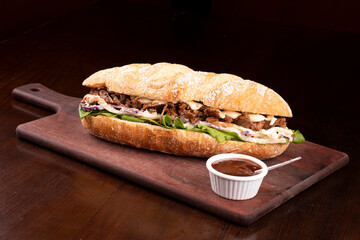 Shredded beef brisket sandwich with barbecue sauce on wooden board viewed from an angle