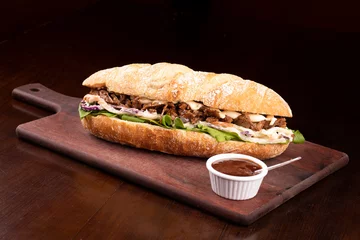 Foto op Canvas Shredded beef brisket sandwich with barbecue sauce on wooden board viewed from an angle © mario