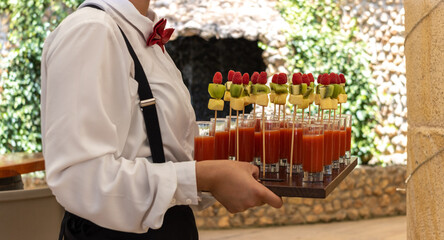 unrecognizable waiter carrying a wooden tray with fruit cocktail canapés at an event celebration