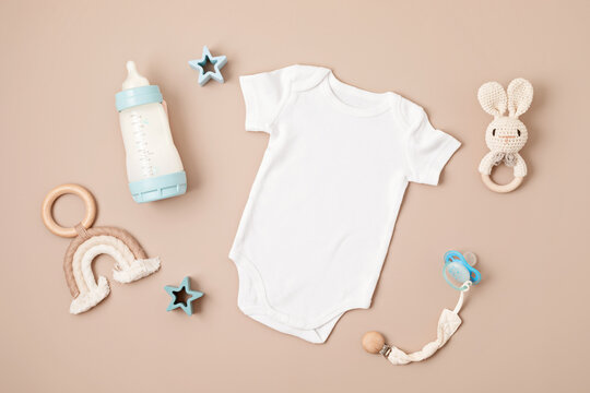 Flat lay with baby sleep accessories with pacifier, pajamas and toys. Newborn sleeping rules concept. Onesie mockup