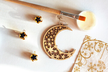 Wooden New year decoration (moon with stars) with golden beads, napkin, a brush on a pot of glue. Top view, flat lay. Decoupage process. Creativity, hobby, DIY concept background