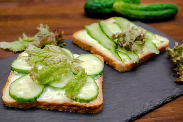 Bruschetta sandwich bread toast with soft green avocado cheese ricotta,fresh cucumbers,basil greenery on wooden cutting board.Tasty healthy vegetarian food,Italian cuisine appetizer.top view flat lay