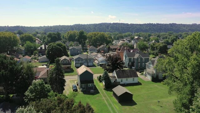 A slow forward moving summer aerial establishing shot of a typical Western Pennsylvania upscale residential neighborhood. Kid on bicycle below. Pittsburgh suburbs.  	