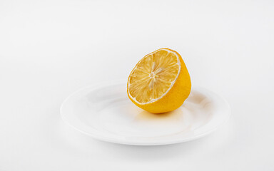 A fresh cut lemon lies on a white plate on a white background. Healthy lifestyle