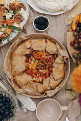 galette with tomatoes on the table top view close-up. dish with tomato pie on the table with other snacks.