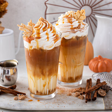 Iced pumpkin spice latte in tall glasses topped with whipped cream