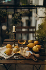 cocktail transparent glass with white wine on a wooden table on the balcony with whole lemons and pieces of parmesan cheese. table with a glass of limoncello and lemons 